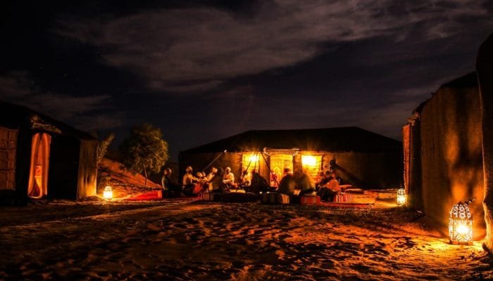 a group of people sitting around a tent in the desert