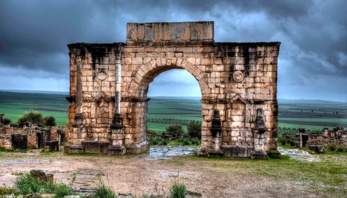 a stone arch with a green field in the background